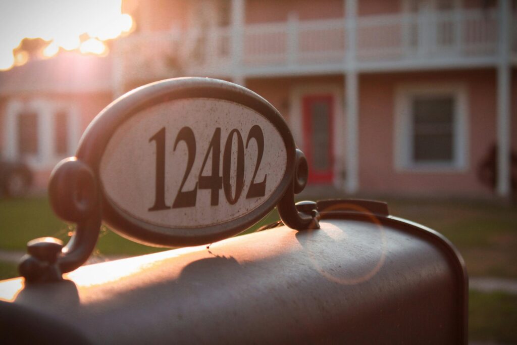 a mailbox with house numbers on it, with a house in the background. this symbolizes the numbers used for address numerology.